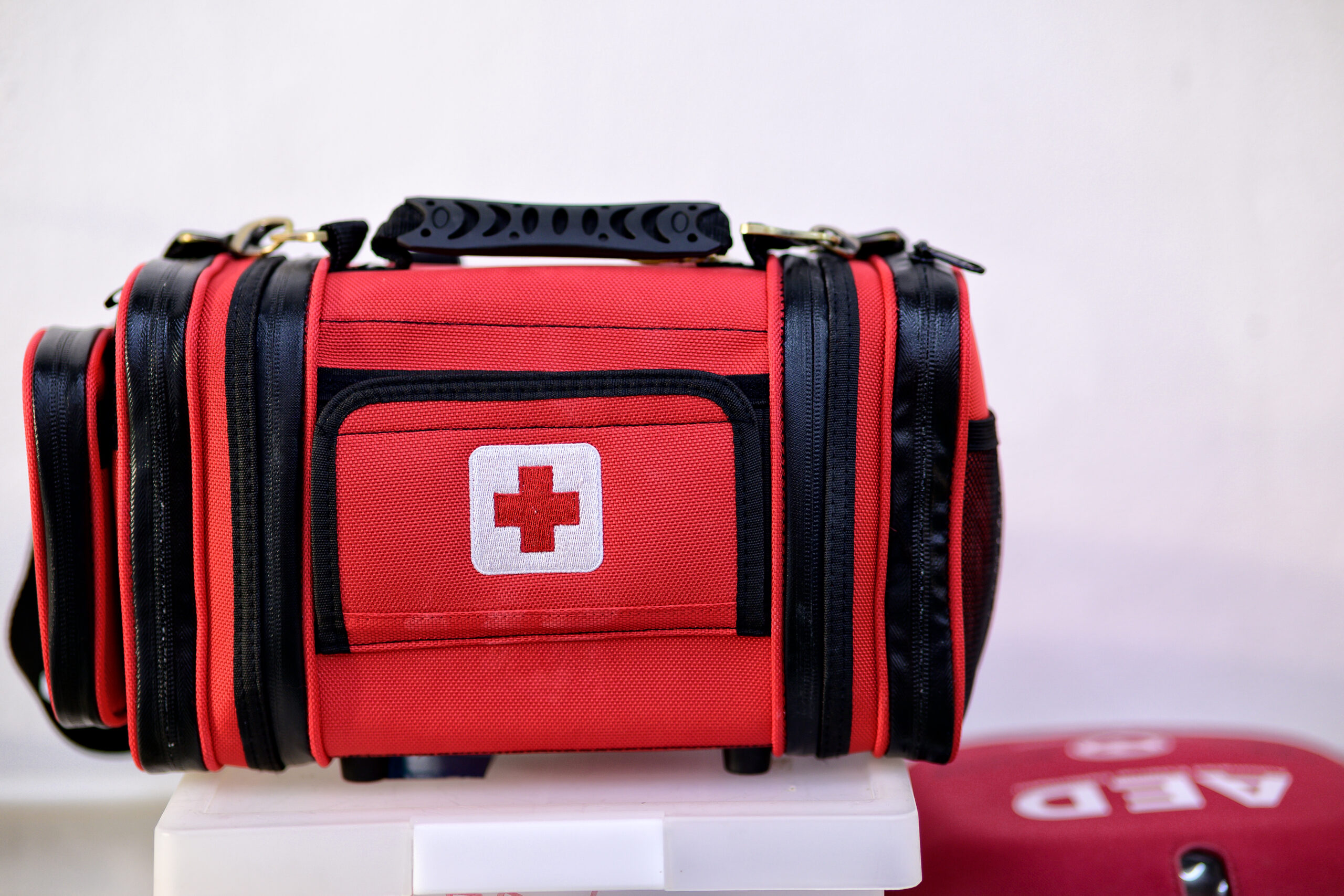 First aid kit bag and AED emergency equipment on white background.