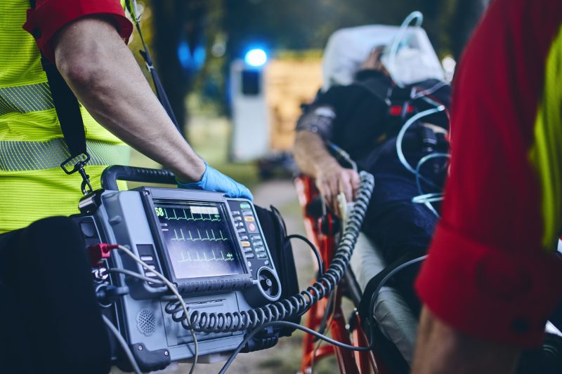 Team of emergency medical service rescuing old patient. Selective focus on heart rate monitor.